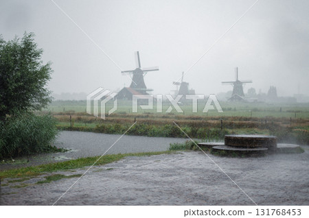 Scenic view of traditional Dutch windmills in Zaandam with changing skies, from calm daylight to approaching rain. 131768453