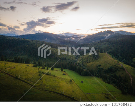 Mountainous countryside scenery at sunset. Dramatic sky above the distant valley. Green fields and trees on the hill. Beautiful nature scenery of carpathians. High quality photo 131768482