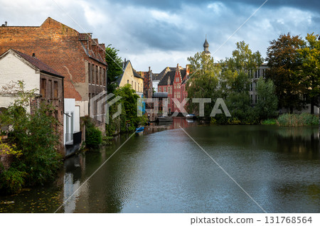 Picturesque canal framed by historic facades and bridges in the heart of Ghent, Belgium. Picturesque canal framed by historic facades and bridges in the heart of Ghent, Belgium. 131768564