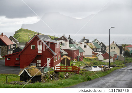 Charming Gjogv village in the Faroe Islands with traditional Scandinavian colorful houses nestled between green hills and the Atlantic coastline. Charming Gjogv village in the Faroe Islands with traditional Scandinavian colorful houses nestled between green hills and the Atlantic coastline. 131768786