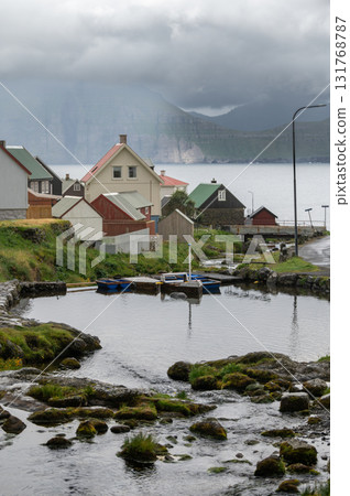 Charming Gjogv village in the Faroe Islands with traditional Scandinavian colorful houses nestled between green hills and the Atlantic coastline. Charming Gjogv village in the Faroe Islands with traditional Scandinavian colorful houses nestled between green hills and the Atlantic coastline. 131768787