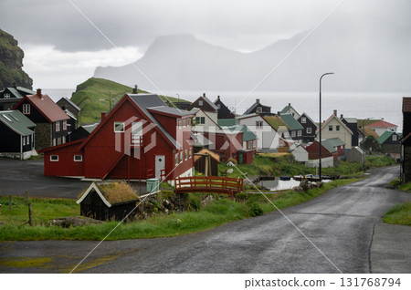 Charming Gjogv village in the Faroe Islands with traditional Scandinavian colorful houses nestled between green hills and the Atlantic coastline. Charming Gjogv village in the Faroe Islands with traditional Scandinavian colorful houses nestled between green hills and the Atlantic coastline. 131768794