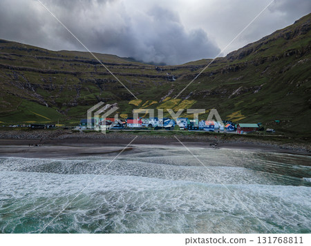 Scenic view of Tjornuvik, a charming village on the north coast of Streymoy, surrounded by dramatic mountains and ocean. Scenic view of Tjornuvik, a charming village on the north coast of Streymoy, surrounded by dramatic mountains and ocean. 131768811