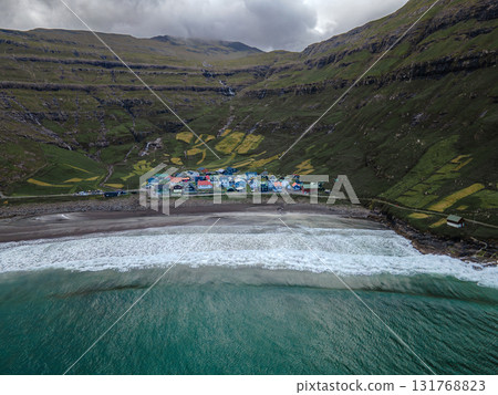 Scenic view of Tjornuvik, a charming village on the north coast of Streymoy, surrounded by dramatic mountains and ocean. Scenic view of Tjornuvik, a charming village on the north coast of Streymoy, surrounded by dramatic mountains and ocean. 131768823