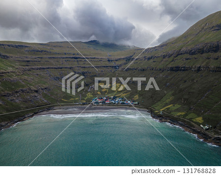 Scenic view of Tjornuvik, a charming village on the north coast of Streymoy, surrounded by dramatic mountains and ocean. Scenic view of Tjornuvik, a charming village on the north coast of Streymoy, surrounded by dramatic mountains and ocean. 131768828