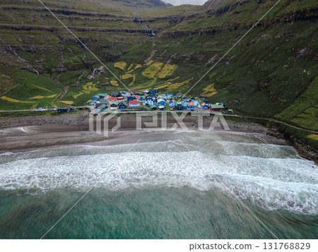Scenic view of Tjornuvik, a charming village on the north coast of Streymoy, surrounded by dramatic mountains and ocean. Scenic view of Tjornuvik, a charming village on the north coast of Streymoy, surrounded by dramatic mountains and ocean. 131768829
