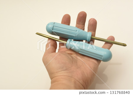 A light blue phillips screwdriver in the master's hand. A hand tool in your hands. A phillips screwdriver. A light blue phillips screwdriver in the master's hand. A hand tool in your hands. A phillips screwdriver. 131768840