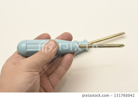 A light blue phillips screwdriver in the master's hand. A hand tool in your hands. A phillips screwdriver. A light blue phillips screwdriver in the master's hand. A hand tool in your hands. A phillips screwdriver. 131768842