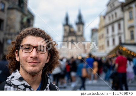 Prague, Czech Republic, August 7, 2023. Portrait of a young Caucasian man looking into the camera in the iconic and crowded Old Town Square. Blurred background, travel destinations. 131769070