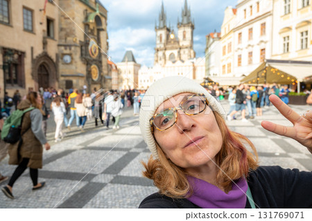 Prague, Czech Republic, August 7, 2023. A middle-aged woman takes a selfie in the iconic, crowded Old Town Square. Blurred background, travel destinations. Prague, Czech Republic, August 7, 2023. A middle-aged woman takes a selfie in the iconic, crowded Old Town Square. Blurred background, travel destinations. 131769071