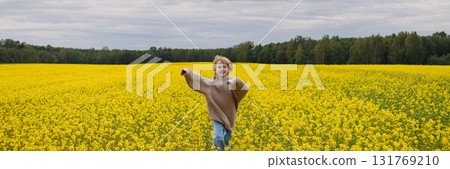 Banner smiling 9 year old girl in oversize sweater running in yellow rapeseed field 131769210