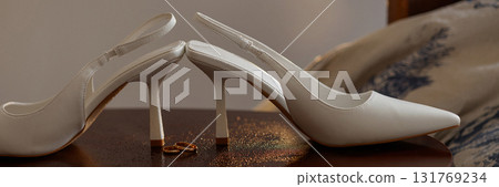 Banner close-up of wedding rings and high heels on wooden floor. Banner close-up of wedding rings and high heels on wooden floor. 131769234
