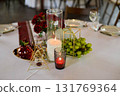 Banquet table for a wedding or anniversary. Red roses. Classic layout. Glasses and white plates. In the fresh air 131769364