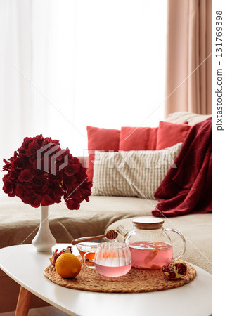 Glass Teapot and Teacup with Pomegranate Drink with Ginger and Citrus on Cozy Sofa with Autumn Decor 131769398