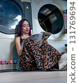 Young Man Reading Sitting In Laundromat 131769694