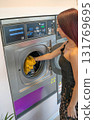 Young Man Taking Yellow Clothes Out of Washing Machine 131769695