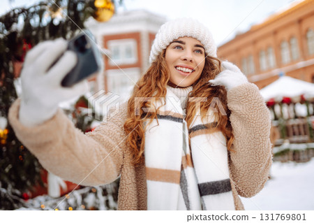 Young tourist uses a smartphone while walking through a Christmas market. 131769801