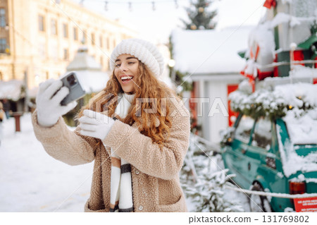 Young tourist uses a smartphone while walking through a Christmas market. Young tourist uses a smartphone while walking through a Christmas market. 131769802