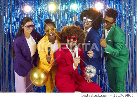 Funny group of young people singing into microphones at karaoke party. 131769965