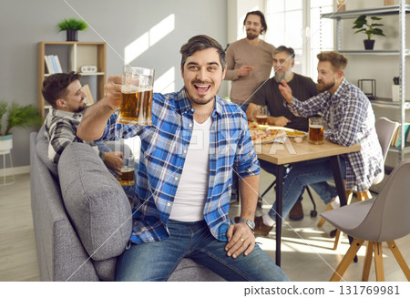 Portrait of man holding glass of beer with a company of friends talking in the background. Portrait of man holding glass of beer with a company of friends talking in the background. 131769981