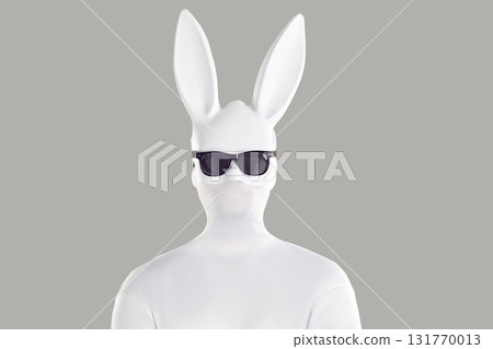 Studio portrait of a man in a white bodysuit, long eared bunny mask, and sunglasses 131770013
