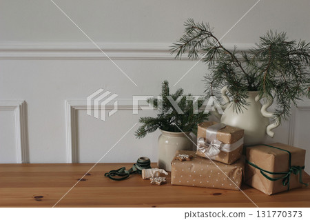 Christmas elegant craft still life. Silk, velvet ribbons, gingerbread cookies on table. Wrapped gifts in brown paper, festive ribbons bow. Birthday wrapping concept. Vases with fir, pine tree branches 131770373