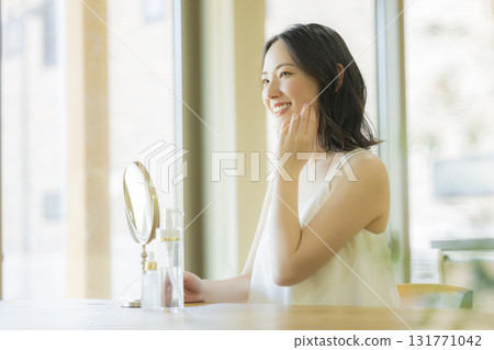 A woman looking in the mirror in the living room A woman looking in the mirror in the living room 131771042
