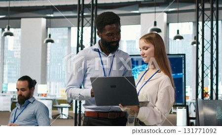 Junior dev and colleague in office reviewing AI system metrics, monitoring performance dashboards. Tech company programmer and young female engineer tuning neural networks, camera A Junior dev and colleague in office reviewing AI system metrics, monitoring performance dashboards. Tech company programmer and young female engineer tuning neural networks, camera A 131771092