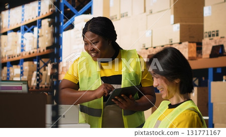 Satisfied coworkers sharing a high five after successful order processing, feeling proud of their teamwork in the industrial retail facility. Fulfillment center employees in workwear. Camera B. 131771167