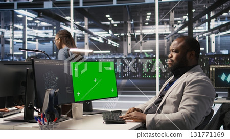 Data center programmer coding on green screen PC, monitoring AI systems. Server hub IT expert uses mockup computer to oversee rackmounts powering deep learning processes, camera A Data center programmer coding on green screen PC, monitoring AI systems. Server hub IT expert uses mockup computer to oversee rackmounts powering deep learning processes, camera A 131771169