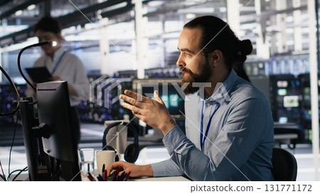 Data center technician discussing with coworker while doing AI software updates. Server room IT specialist and colleague chatting, optimizing infrastructure using artificial intelligence, camera A 131771172