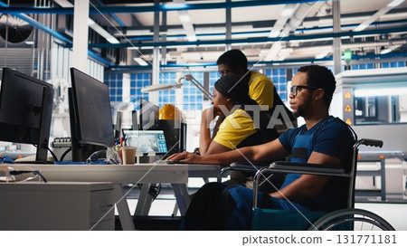 African american wheelchair user working in solar panel factory, optimizing systems for renewable energy. Engineer examines robot arms automation in a disability friendly power plant. Camera B. 131771181