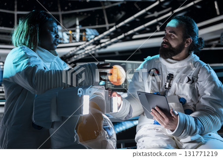 Team of astronauts in starship travelling to Mars conducting safety checks using tablet. Teamworking cosmonauts flying to red planet operating spacecraft control interface, calibrating sensors Team of astronauts in starship travelling to Mars conducting safety checks using tablet. Teamworking cosmonauts flying to red planet operating spacecraft control interface, calibrating sensors 131771219