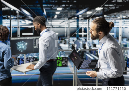 Worried technician in server room detecting hacking attempt targeting data systems and panicking about data breach. Engineering team under pressure by virus activity, emergency protocol. Worried technician in server room detecting hacking attempt targeting data systems and panicking about data breach. Engineering team under pressure by virus activity, emergency protocol. 131771230