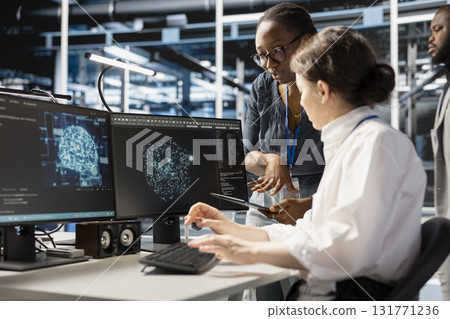 Data center system administrators using computer to visualize artificial intelligence neural networks made up of interconnected nodes. Server hub coworkers doing brainstorming, overseeing AI systems 131771236