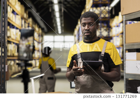 Black fulfillment center staff recording an advertisement vlog to promote large scale industrial and retail activity, showcasing parcel delivery workflow. Large business commercial ad video. 131771269
