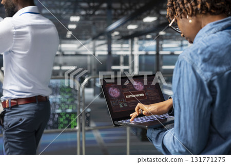 Stressed panicked woman handling cybercriminal threat response, trying to save data center sever rigs during security breach. Worried engineer reads a critical error alert on laptop. 131771275