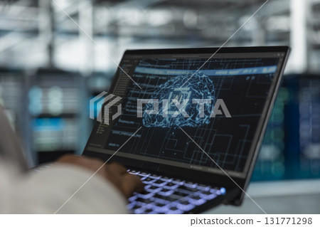 Close up of engineer using laptop in data center housing advanced infrastructure used for AI workloads. Server room IT professional running artificial intelligence code to reduce rigs latency 131771298