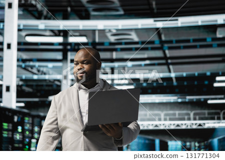 Data center admin using laptop to automate errors detection, troubleshooting backend operations. Server hub IT expert monitoring components for potential failures, conducting regular security audits 131771304