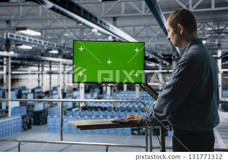 Server hub IT expert uses mockup chroma key computer, implementing efficiency optimizations. Data center admin using green screen PC monitor, implementing efficiency optimizations in across rigs 131771312