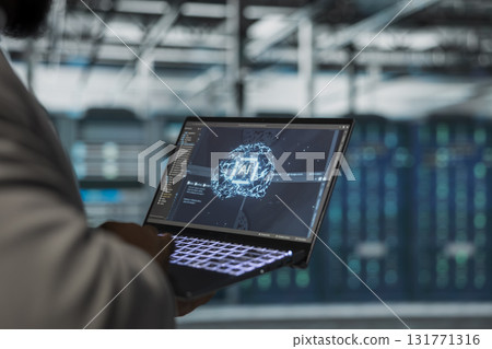 Close up of engineer using laptop in data center housing advanced equipment used for complex AI calculations. Server room IT professional running artificial intelligence code to optimize performance 131771316