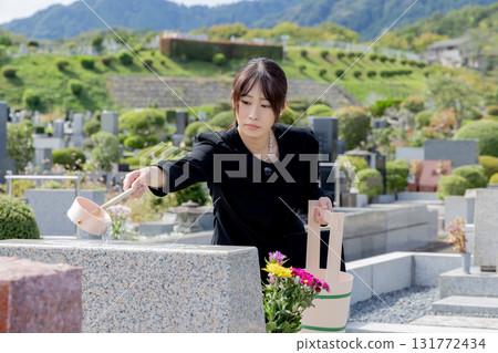 A woman cleaning a tombstone 131772434
