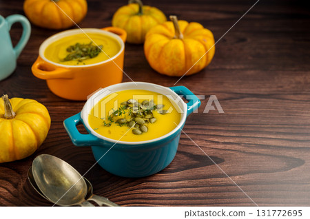 Pumpkin soup in ceramic bowls, wooden background, fresh pumpkins. Autumn food, copy space 131772695