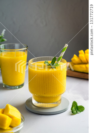 Mango banana smoothie in a glass with fresh fruit and mint, copy space 131772719