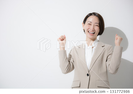 一位年輕美麗的女人站在白色背景上，穿著米色西裝，商務，上身，看著相機，拳頭泵，銷售等 131772986