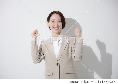A young beautiful woman standing in a beige suit, business, upper body, looking at the camera, fist pump, sales, etc., on a white background A young beautiful woman standing in a beige suit, business, upper body, looking at the camera, fist pump, sales, etc., on a white background 131772987