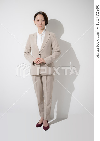 Beautiful business woman in a beige suit, standing looking at the camera, white background Beautiful business woman in a beige suit, standing looking at the camera, white background 131772990