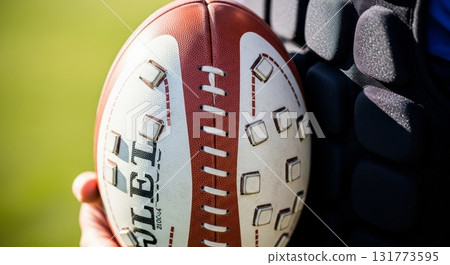 Close-up of hands holding a football with detailed stitching 131773595