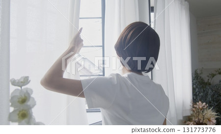 Woman opening curtain Woman opening curtain 131773776