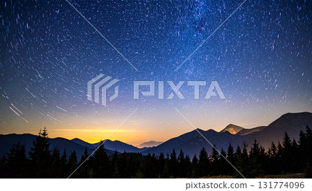 A glittering starry sky and silhouettes of mountains and forests 131774096